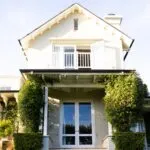 Modern house with white facade, lush greenery, showcasing elegant architecture and inviting entrance, relevant to HVAC services by Kelly's Heating and Air for local homeowners.