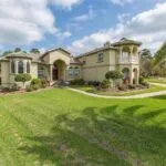 Elegant home exterior with manicured lawn, palm trees, and driveway, representing comfort and quality HVAC services by Kelly’s Heating and Air in Highland Village, TX.
