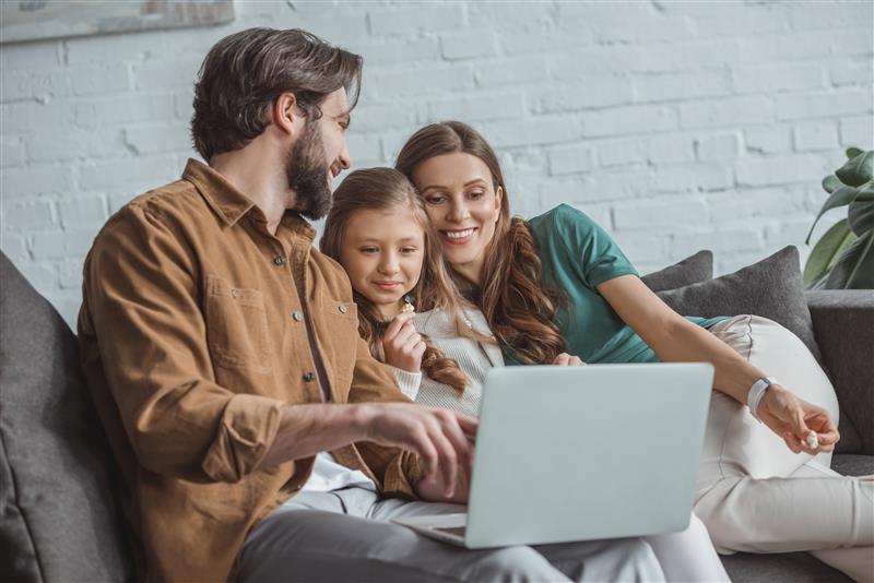Family using a laptop on the couch. Home financing options may be available to help families achieve their dreams. Lewisville, TX.