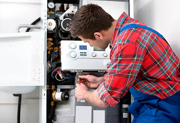 Heating Repair Plano: Man in plaid shirt repairing a modern furnace with visible gauges and wires. Professional heating services in Lewisville, TX.